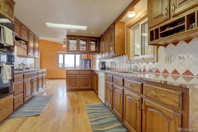 kitchen with kitchen peninsula, decorative backsplash, white dishwasher, light wood-type flooring, and sink