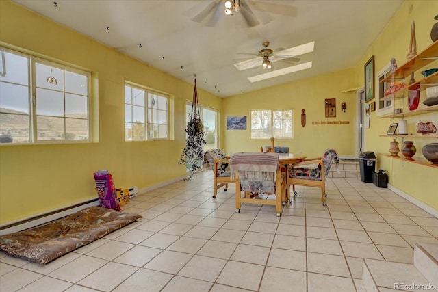 dining room with vaulted ceiling with skylight, ceiling fan, baseboard heating, and light tile patterned floors