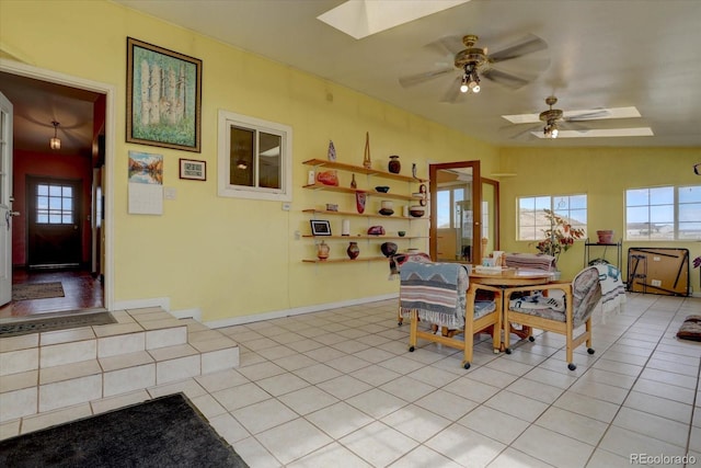 tiled dining room with vaulted ceiling with skylight and ceiling fan