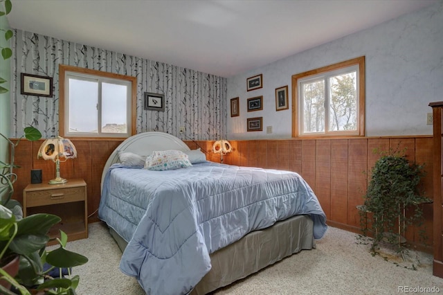 bedroom with light carpet and wood walls