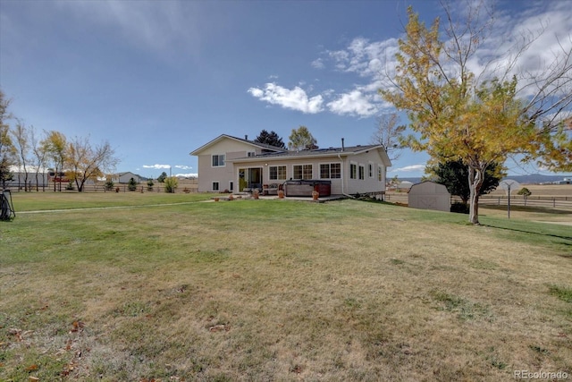 back of house with a storage shed, a hot tub, and a lawn