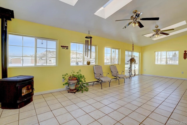 sitting room featuring a wood stove, light tile patterned floors, and vaulted ceiling with skylight