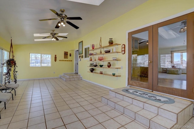 empty room featuring light tile patterned flooring, vaulted ceiling, french doors, and a wealth of natural light