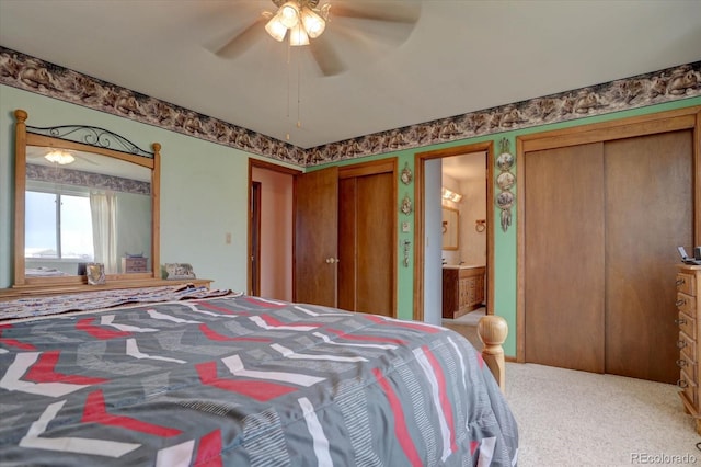 bedroom with carpet, connected bathroom, ceiling fan, and multiple closets