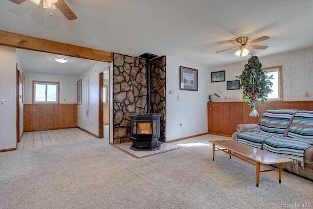 living room with light carpet, a wood stove, beamed ceiling, and ceiling fan