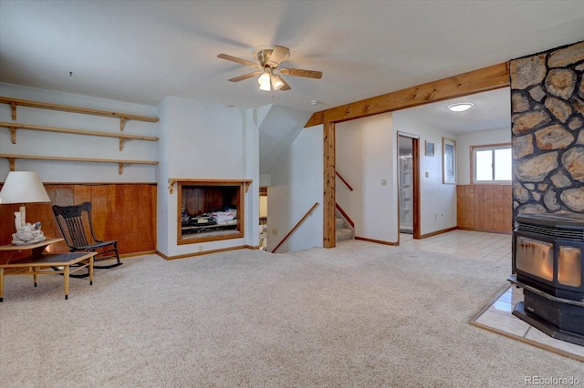 living room featuring ceiling fan, a wood stove, and light colored carpet