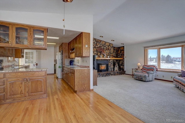 11810 Mesa View Rd, Larkspur, CO 80118 - kitchen with lofted ceiling, brown cabinetry, open floor plan, glass insert cabinets, and light wood-type flooring