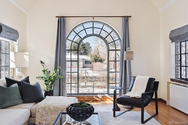 sitting room featuring radiator heating unit, ornamental molding, and light wood-type flooring