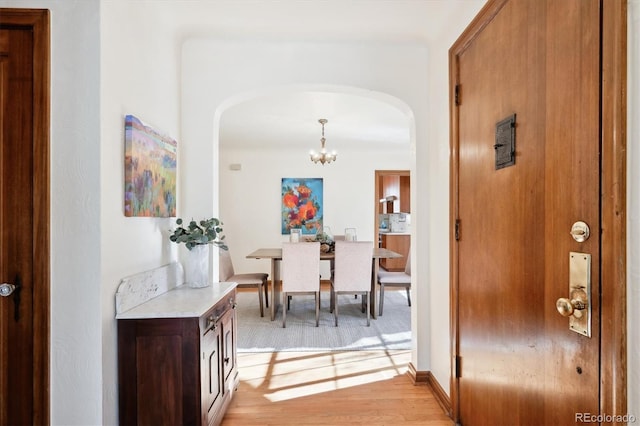 corridor featuring an inviting chandelier and light hardwood / wood-style flooring