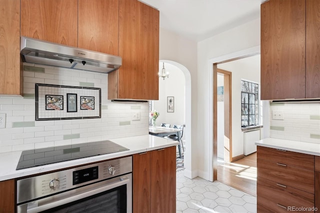 kitchen featuring black electric stovetop, backsplash, and oven