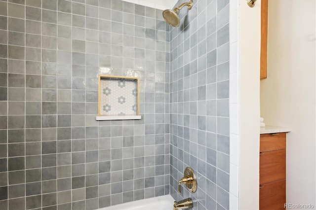 bathroom featuring tiled shower / bath combo and vanity