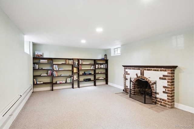 basement with light carpet, a baseboard heating unit, and a brick fireplace