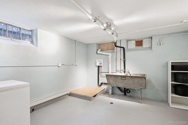 basement featuring baseboard heating and a textured ceiling