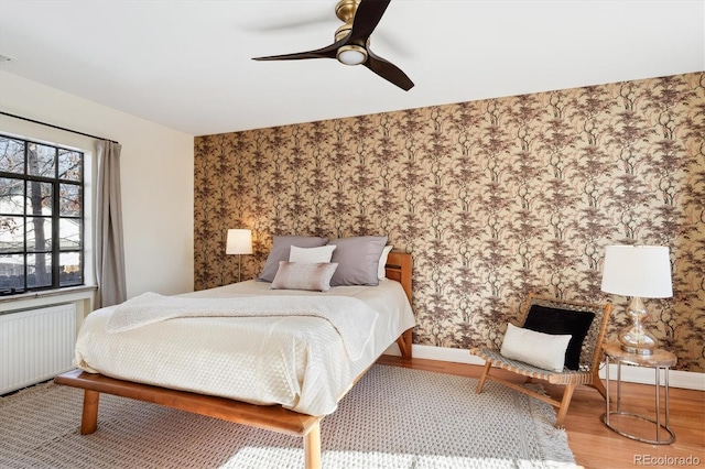 bedroom featuring hardwood / wood-style flooring, radiator, and ceiling fan