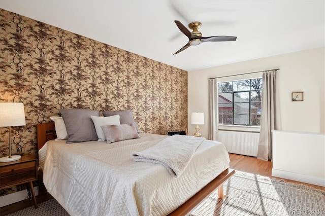 bedroom featuring radiator heating unit, light hardwood / wood-style floors, and ceiling fan