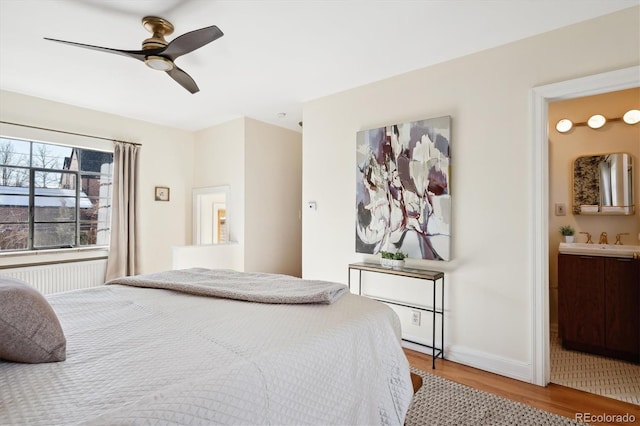 bedroom with hardwood / wood-style flooring, ensuite bath, ceiling fan, and sink