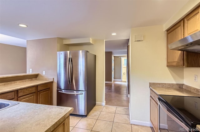 8759 E Roundtree Ave, Greenwood Village, CO 80111 - kitchen with freestanding refrigerator, electric range oven, light tile patterned floors, recessed lighting, and brown cabinetry