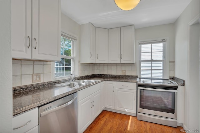 4480 S Pennsylvania St, Englewood, CO 80113 - kitchen with appliances with stainless steel finishes, white cabinetry, light wood finished floors, backsplash, and dark stone counters