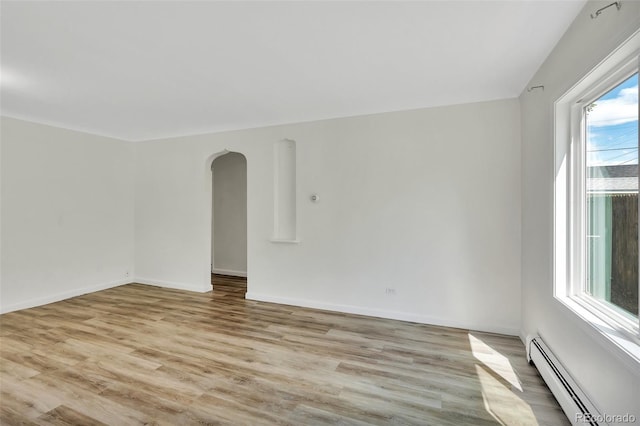 4480 S Pennsylvania St, Englewood, CO 80113 - unfurnished room featuring a baseboard heating unit, arched walkways, and light wood-style flooring