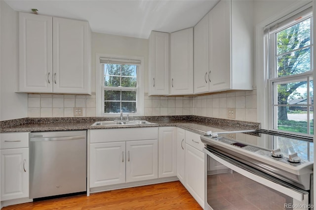 4480 S Pennsylvania St, Englewood, CO 80113 - kitchen featuring appliances with stainless steel finishes, white cabinetry, decorative backsplash, and light wood-style floors