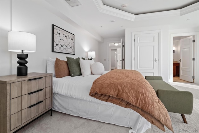 bedroom featuring visible vents, a tray ceiling, ornamental molding, ensuite bathroom, and light carpet