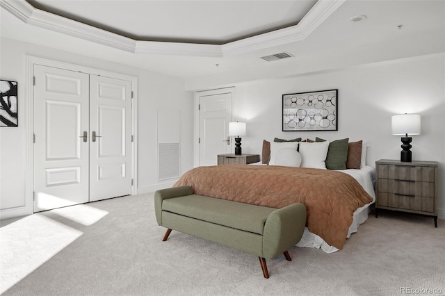 bedroom with ornamental molding, a tray ceiling, and light colored carpet