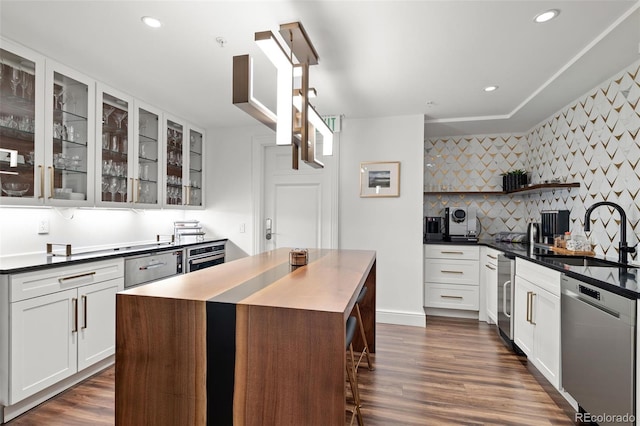 kitchen featuring backsplash, stainless steel dishwasher, sink, white cabinets, and a center island