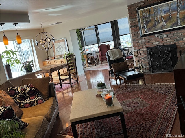 living room with a fireplace, wood finished floors, visible vents, and an inviting chandelier