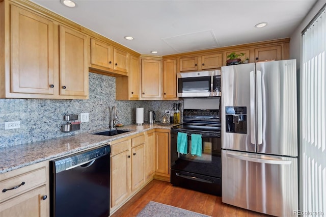 kitchen featuring light stone countertops, light brown cabinets, a sink, wood finished floors, and black appliances