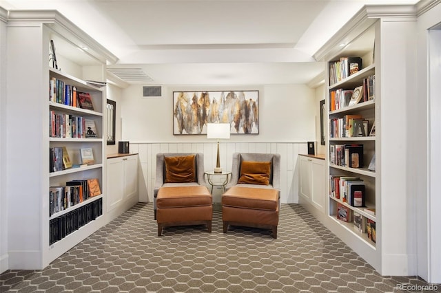 sitting room with built in features, a wainscoted wall, and visible vents