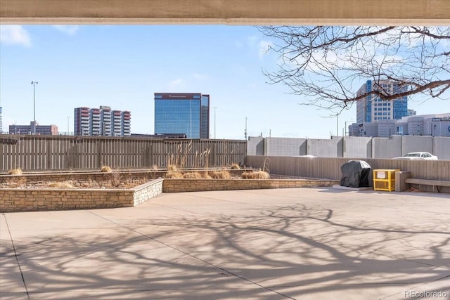 view of patio with fence and a city view