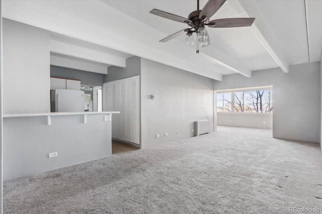 unfurnished living room featuring a ceiling fan, carpet, and beam ceiling