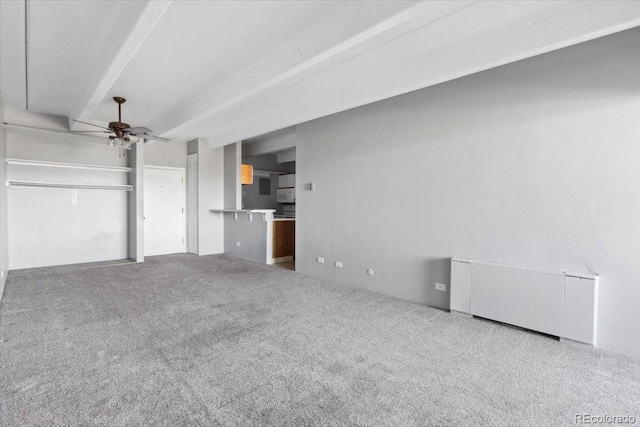 unfurnished living room with ceiling fan, beamed ceiling, and carpet flooring