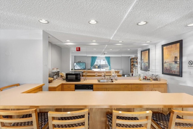 kitchen featuring recessed lighting, light countertops, a sink, black microwave, and dishwashing machine