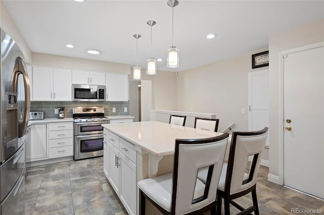 6504 W 85th Ave, Arvada, CO 80003 - kitchen with appliances with stainless steel finishes, a kitchen breakfast bar, tasteful backsplash, light countertops, and a kitchen island