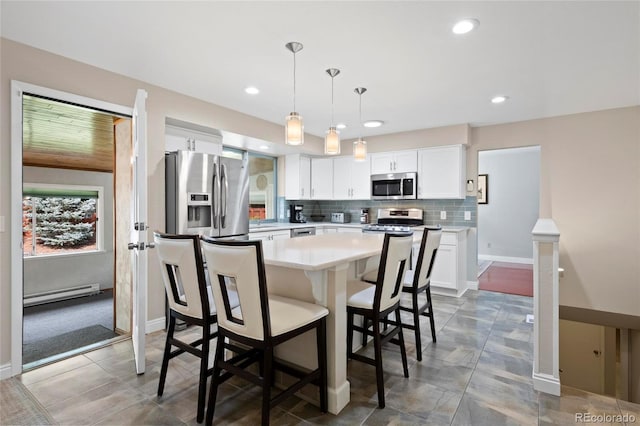 6504 W 85th Ave, Arvada, CO 80003 - kitchen with appliances with stainless steel finishes, light countertops, a breakfast bar area, white cabinetry, and decorative backsplash