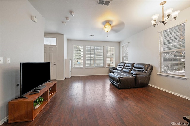 living room with ceiling fan with notable chandelier, baseboards, visible vents, and dark wood finished floors