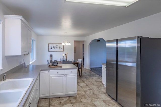 8800 W Kentucky Ave, Lakewood, CO 80226 - kitchen with freestanding refrigerator, a sink, white cabinets, a chandelier, and a peninsula