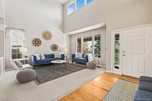 living room with a towering ceiling, baseboards, and wood finished floors