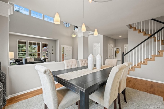 dining area with stairway, baseboards, a high ceiling, and wood finished floors