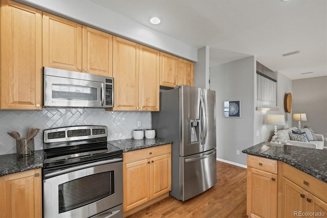 kitchen with tasteful backsplash, light wood-style flooring, appliances with stainless steel finishes, and dark stone countertops