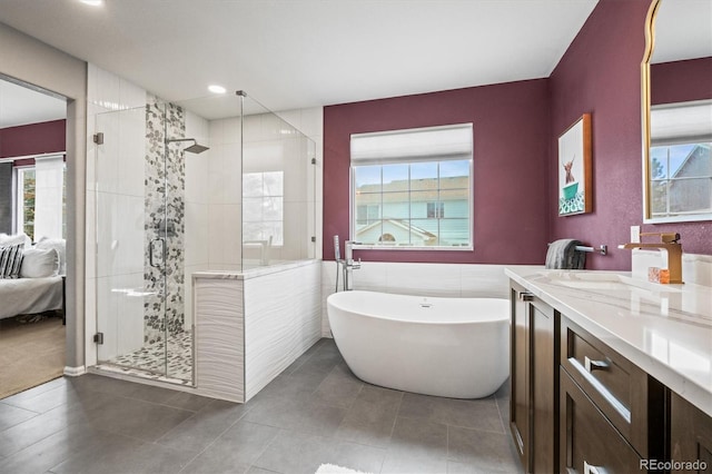 ensuite bathroom featuring a shower stall, connected bathroom, tile walls, a soaking tub, and vanity