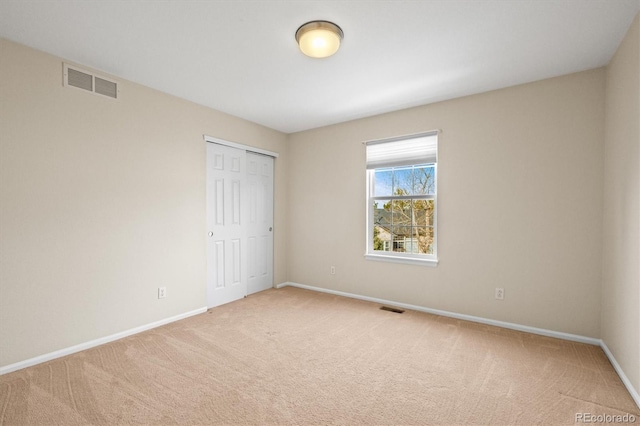 unfurnished bedroom with light carpet, visible vents, a closet, and baseboards