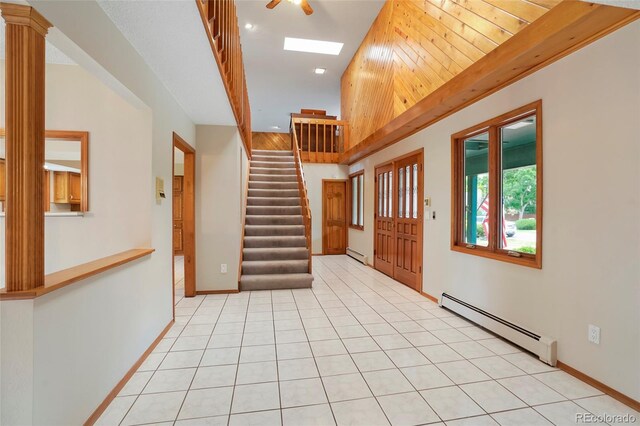 foyer with a high ceiling, a baseboard radiator, and light tile floors