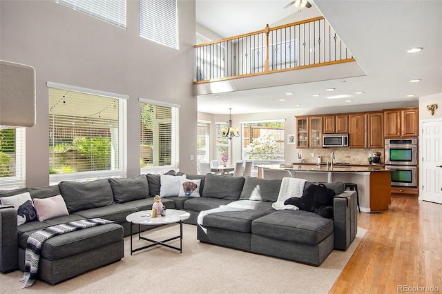 living room with a notable chandelier, sink, and light wood-type flooring