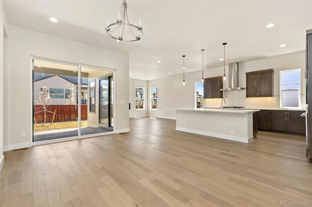 1711 Branching Canopy Dr, Windsor, CO 80550 - kitchen featuring wall chimney exhaust hood, open floor plan, light wood-style floors, dark brown cabinets, and recessed lighting