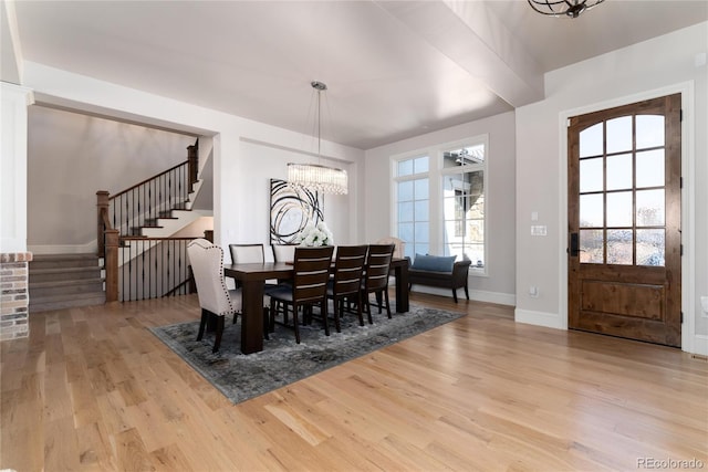 dining area featuring a chandelier, stairway, baseboards, and wood finished floors