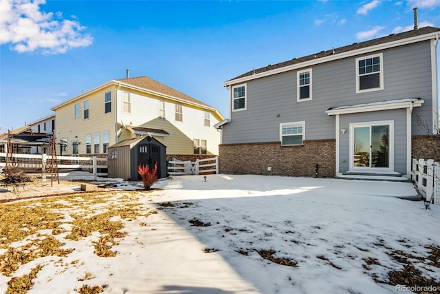 snow covered house featuring a storage shed