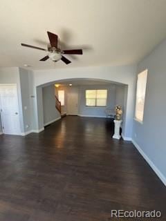 unfurnished living room with dark wood-type flooring and ceiling fan