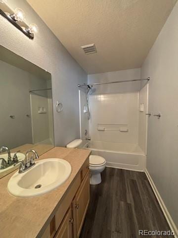 full bathroom featuring a textured ceiling, washtub / shower combination, toilet, vanity, and wood-type flooring